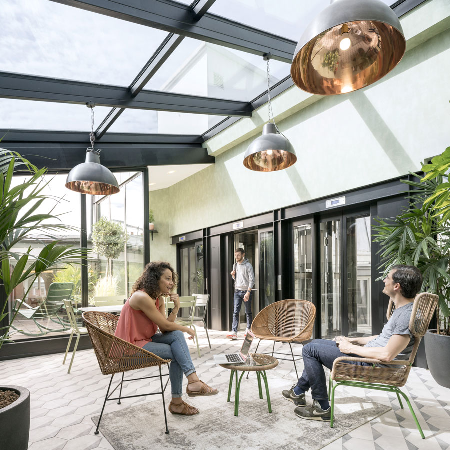 Users step out of the elevator into a conservatory space. 