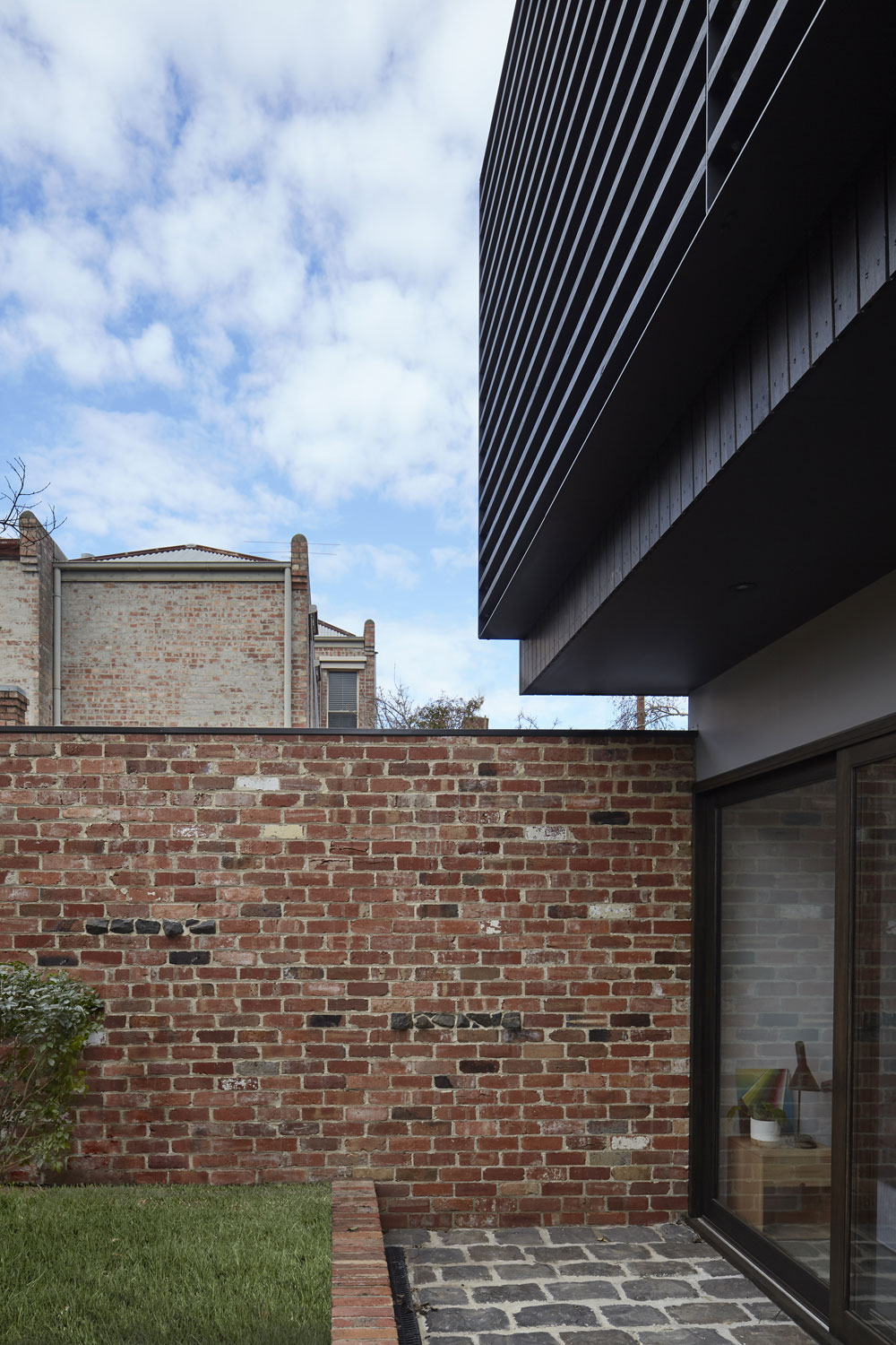 The recycled brick wall extends out from the house enclosing the garden from the laneway.