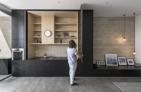 Black cabinet doors reveal a kitchen