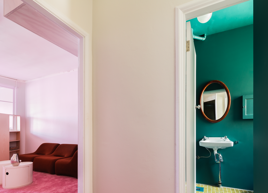 Mid-afternoon light transforms the interior from white to pink, while an emerald bathroom provides a striking contrast