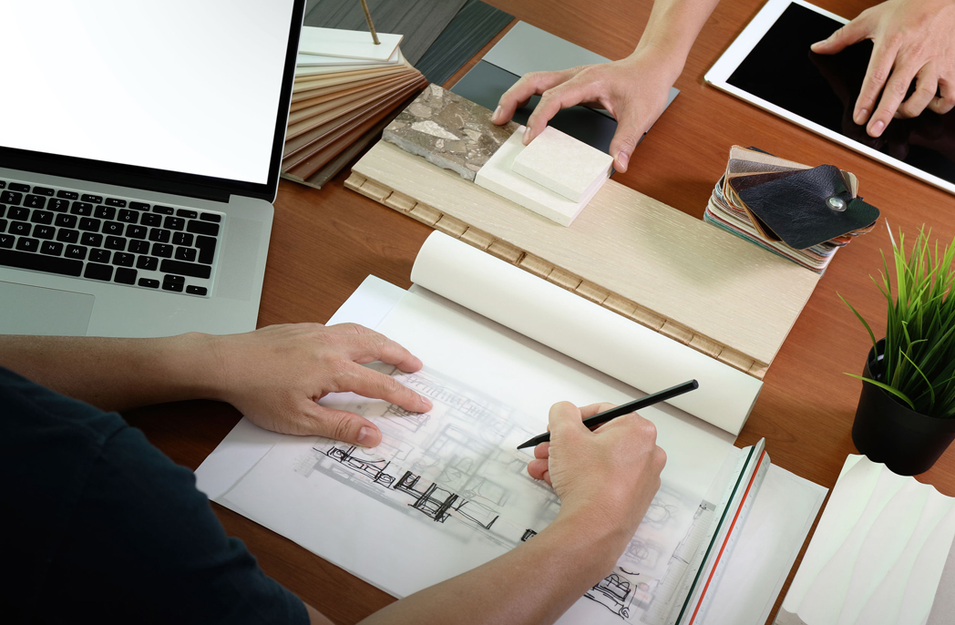 view of two colleagues interior designers discussing data with blank screen new modern computer laptop and pro digital tablet with sample material on wooden desk as concept