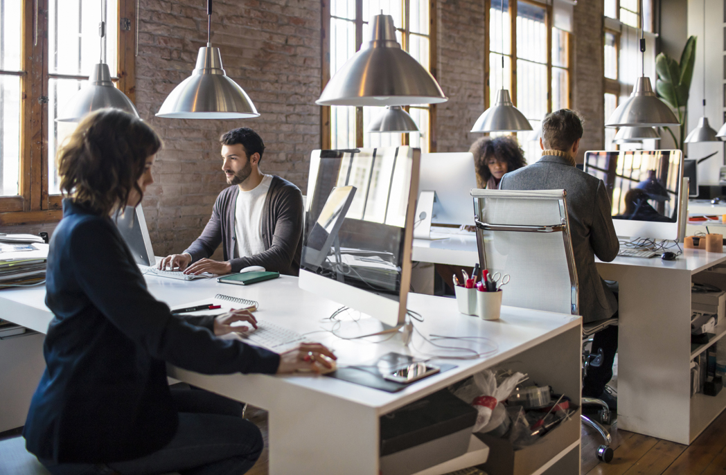 Young people working on a startup office, all are at their desks very concentrated.