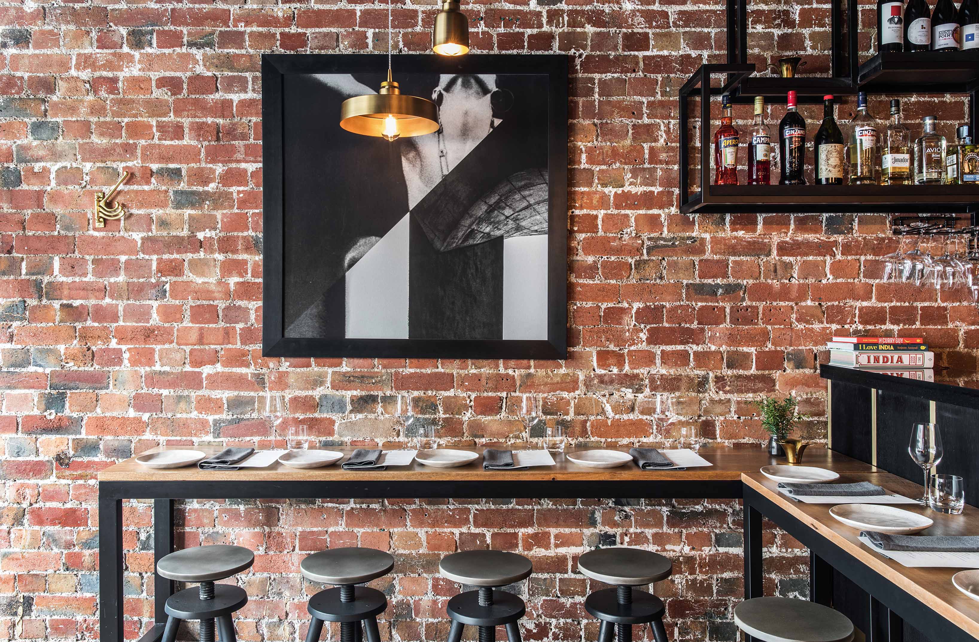 High hardwood timber tables line the exposed brick wall
