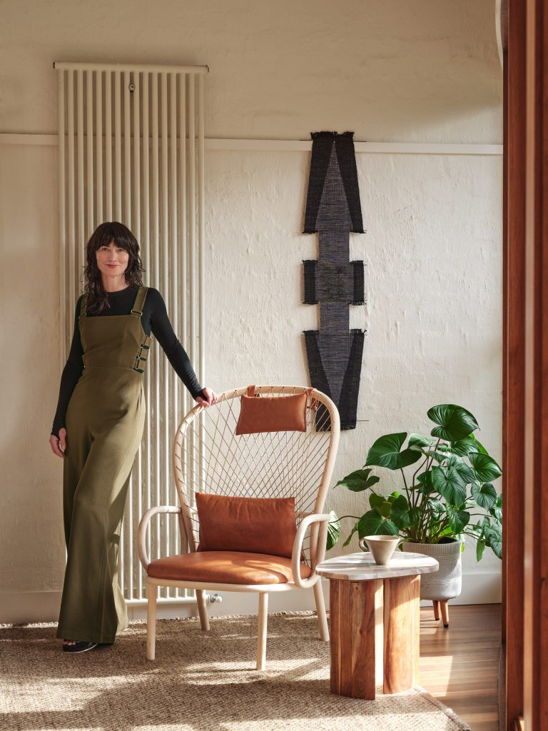 Kim Kneipp in a room with art, beautiful furniture and a lush plant