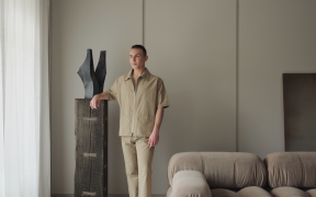 Joss Knight, interior designer, standing in a living room with a neutral earth toned colour palette.