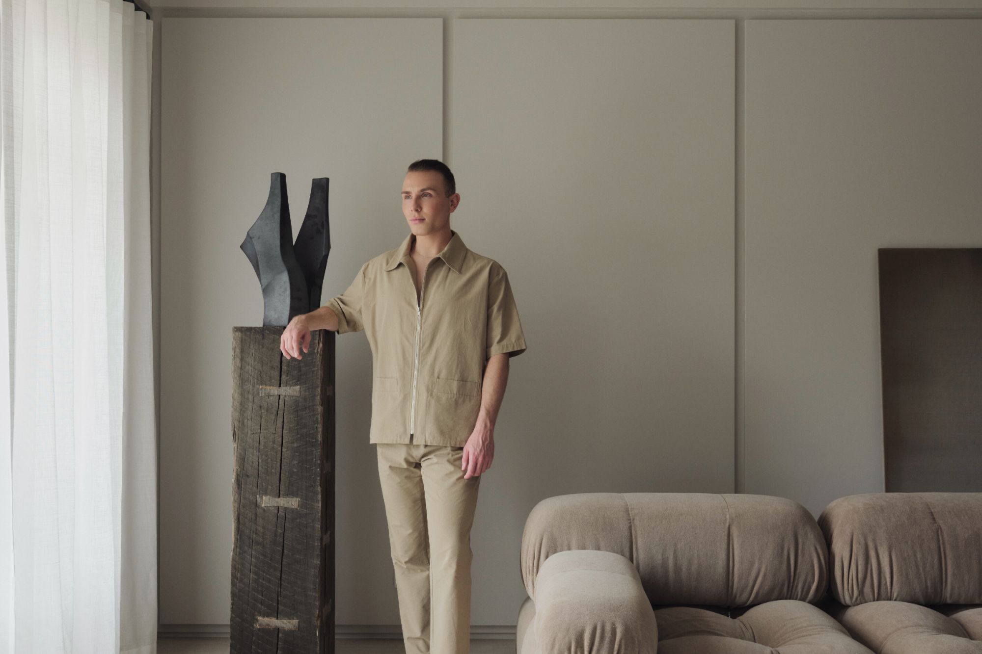 Joss Knight, interior designer, standing in a living room with a neutral earth toned colour palette.