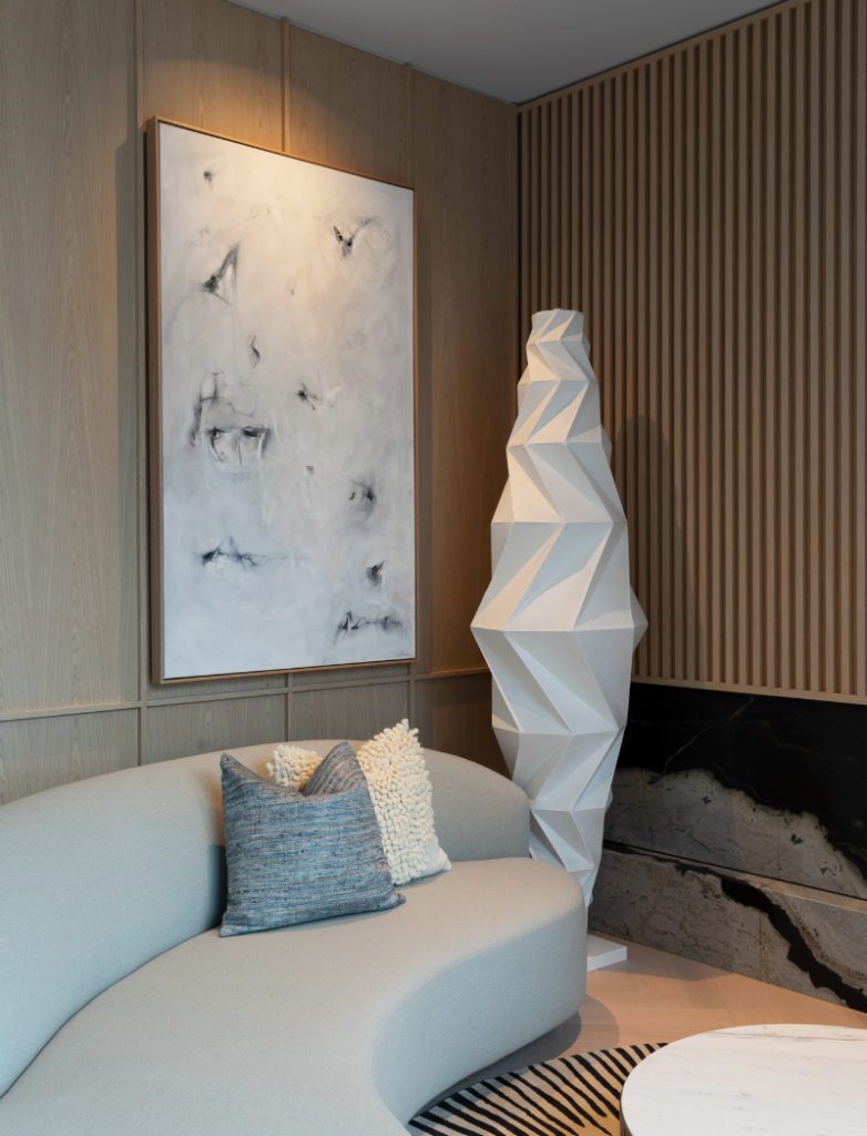 Lanson Place. An interior corner with a large croissant shaped light in the corner, a curved grey sofa to the left and a monochrome artwork on the wall.