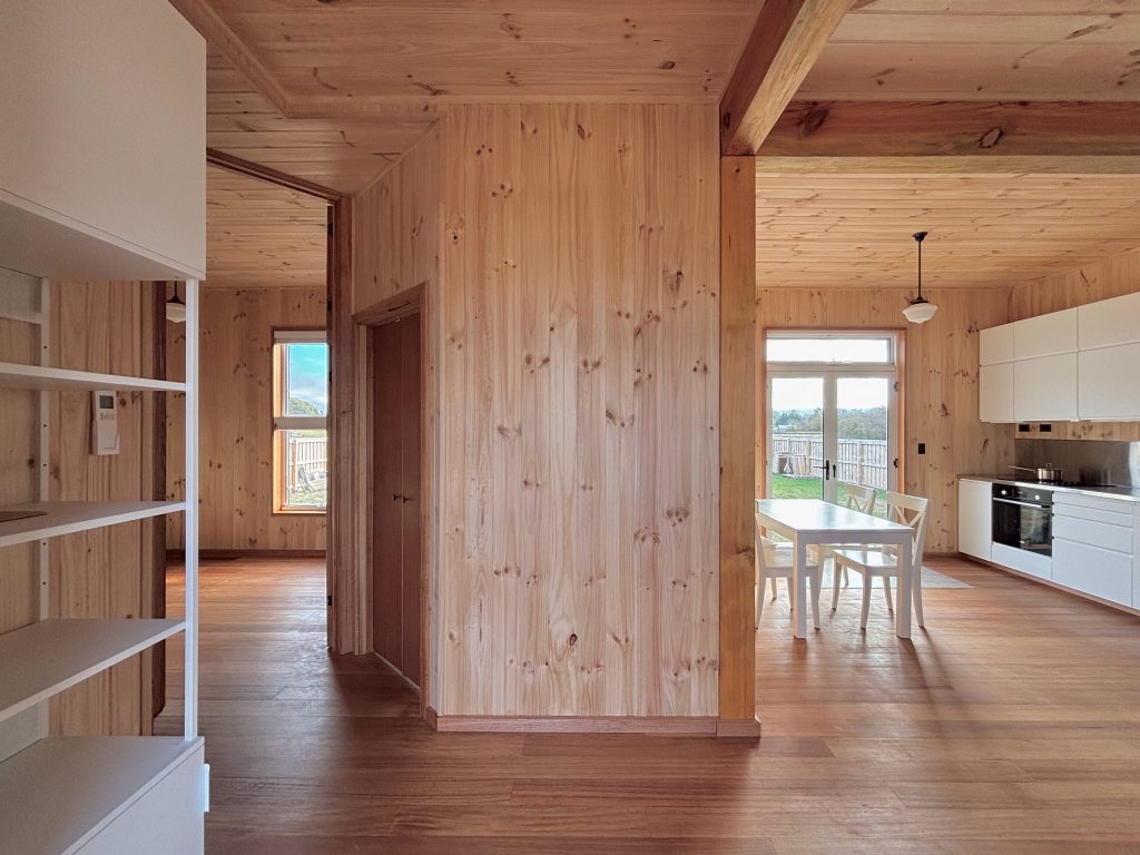 Jiri Lev, wood-lined interior with kitchen on right and empty spaces in foreground and to the left.