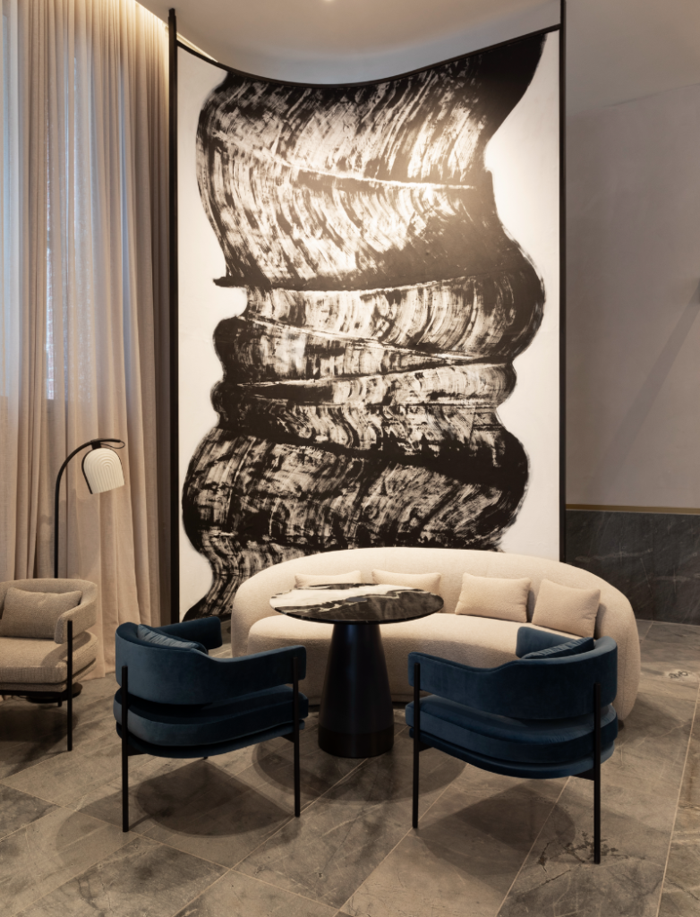 Lanson Place. Interior of two chairs and a sofa around a small table, in front of a large wavy artwork.